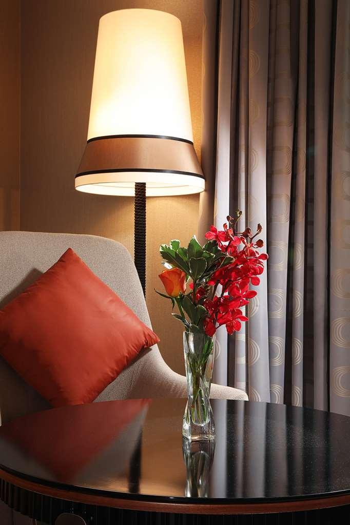 โรงแรมแกรนด์ คอสโมโพลิตัน - ดูไบ ห้อง รูปภาพ The photo shows a cozy corner with a modern armchair that has a light gray fabric. It features a bright orange decorative pillow on one side. Next to the chair is a stylish lamp with a wide shade that emits a warm light. On a small table beside the c