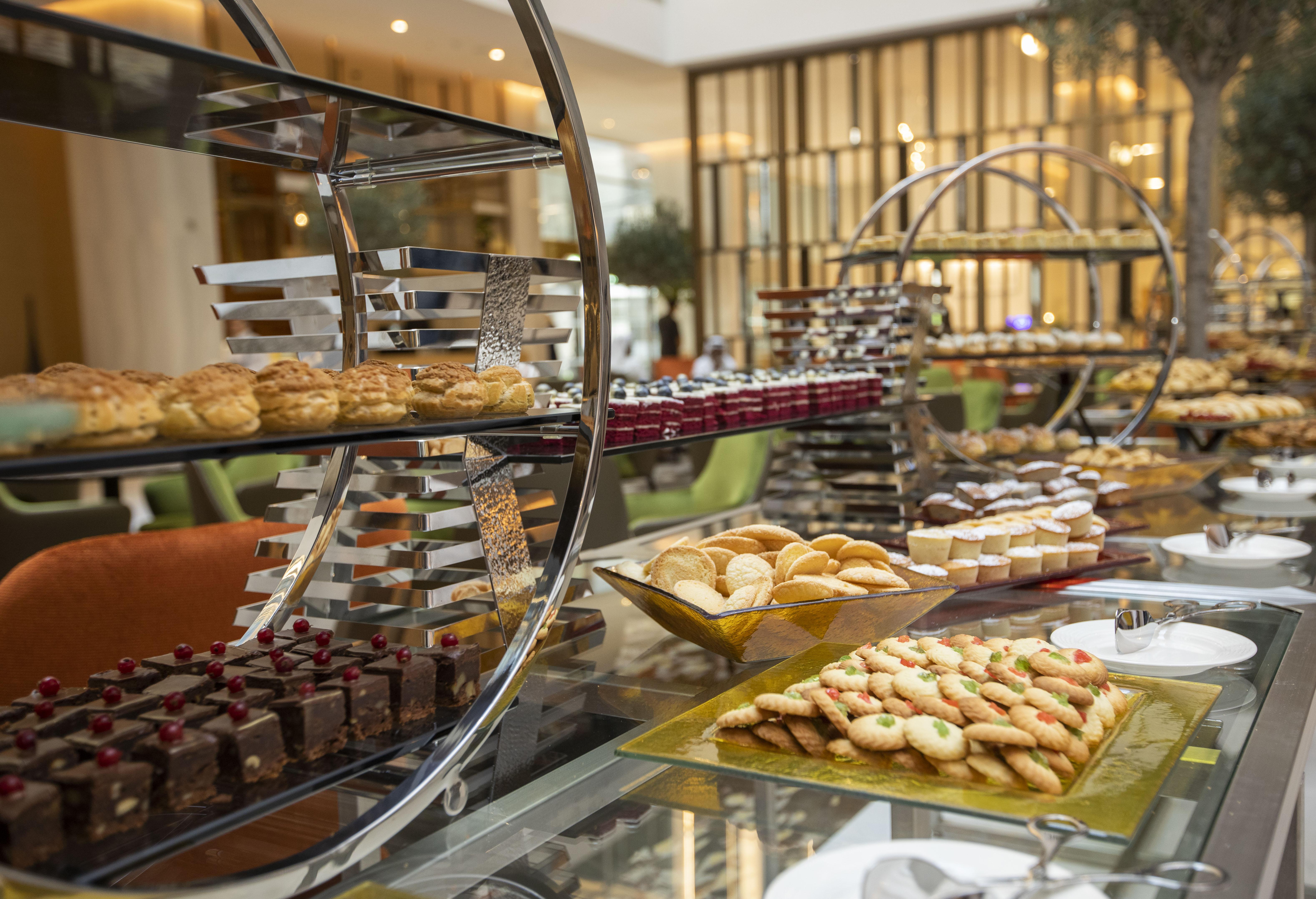 โรงแรมแกรนด์ คอสโมโพลิตัน - ดูไบ ภายนอก รูปภาพ The photo showcases an elegant dessert display featuring a variety of baked goods. There are multiple tiers of treats, including pastries, cookies, and chocolates. On the lower tier, there appears to be an assortment of cookies arranged on a rectangu