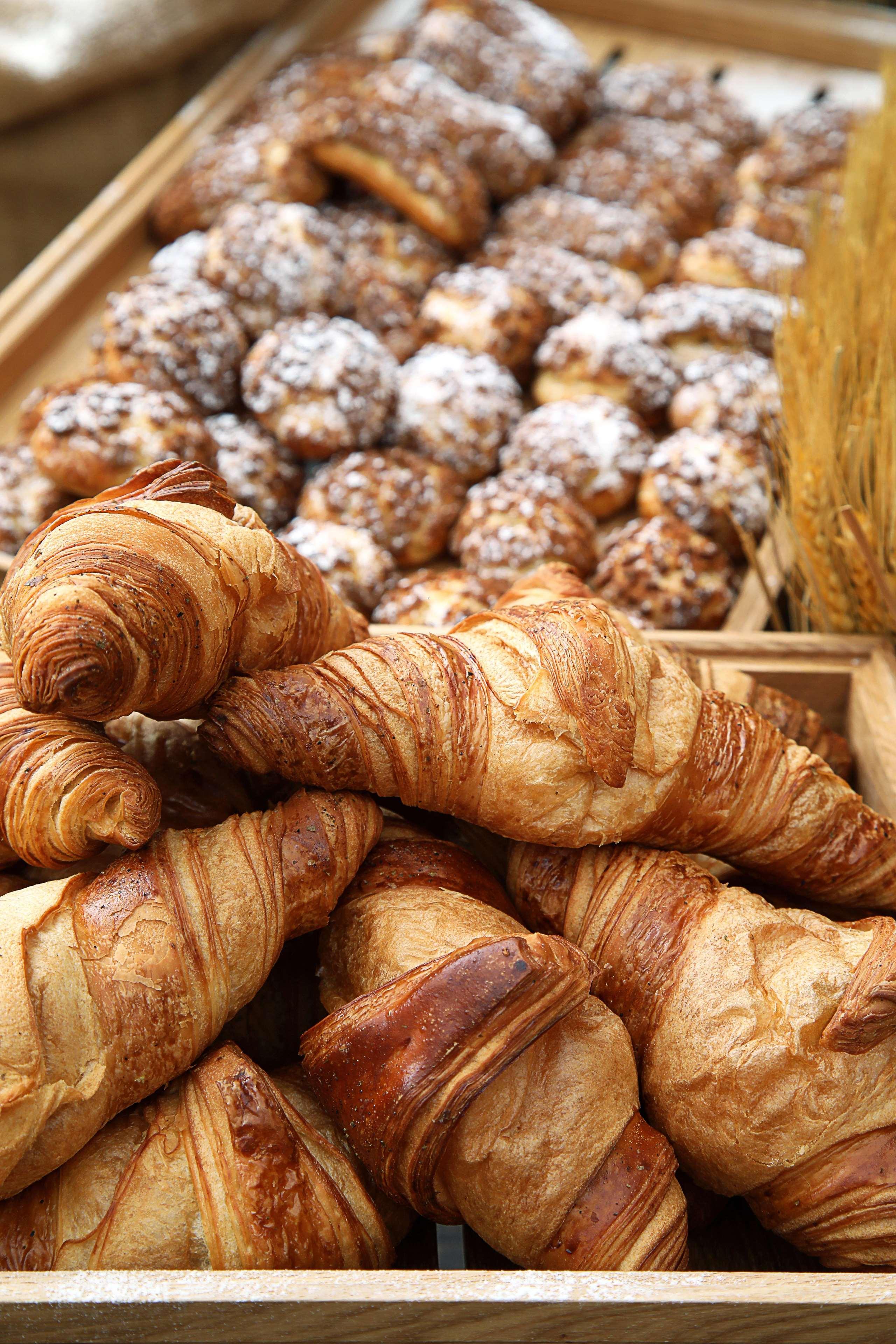 โรงแรมแกรนด์ คอสโมโพลิตัน - ดูไบ ภายนอก รูปภาพ The photo displays a selection of baked goods, prominently featuring several golden-brown croissants. The croissants are flaky and have a distinct, spiral shape characteristic of this pastry. In the background, there are additional baked items, possi