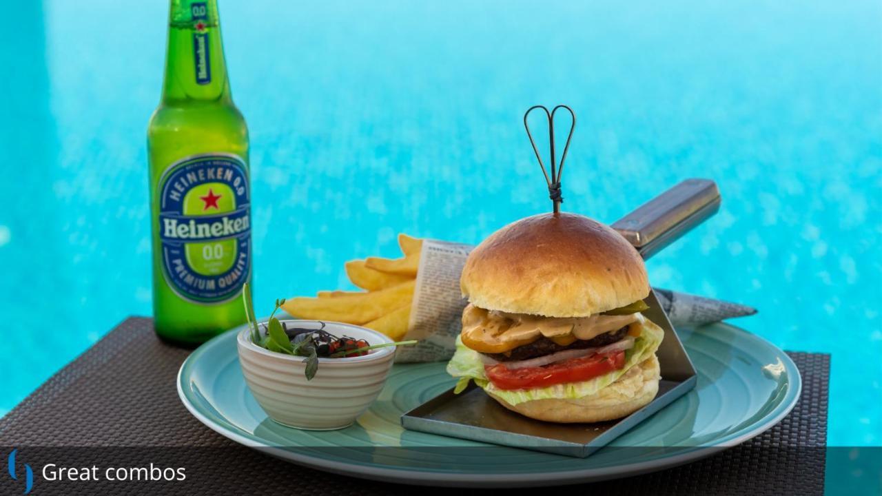 โรงแรมแกรนด์ คอสโมโพลิตัน - ดูไบ ภายนอก รูปภาพ The photo features a delicious-looking meal consisting of a hamburger, accompanied by French fries and a small dish of sauce or dip. The hamburger is topped with lettuce, tomato, and what appears to be a grilled chicken patty, all held together by a 