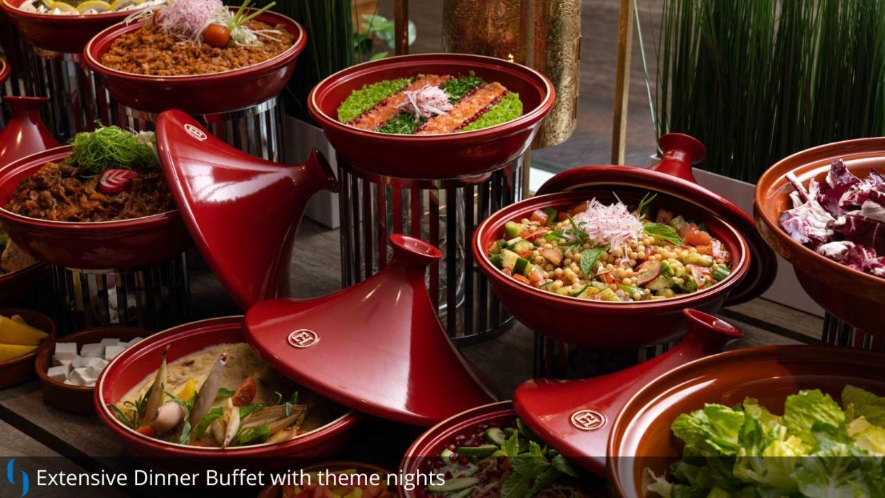 โรงแรมแกรนด์ คอสโมโพลิตัน - ดูไบ ภายนอก รูปภาพ The photo displays an assortment of colorful dishes arranged in red ceramic containers. Each dish appears to have various ingredients, likely featuring a mix of vegetables, proteins, and grains. The presentation is visually appealing, with vibrant gr