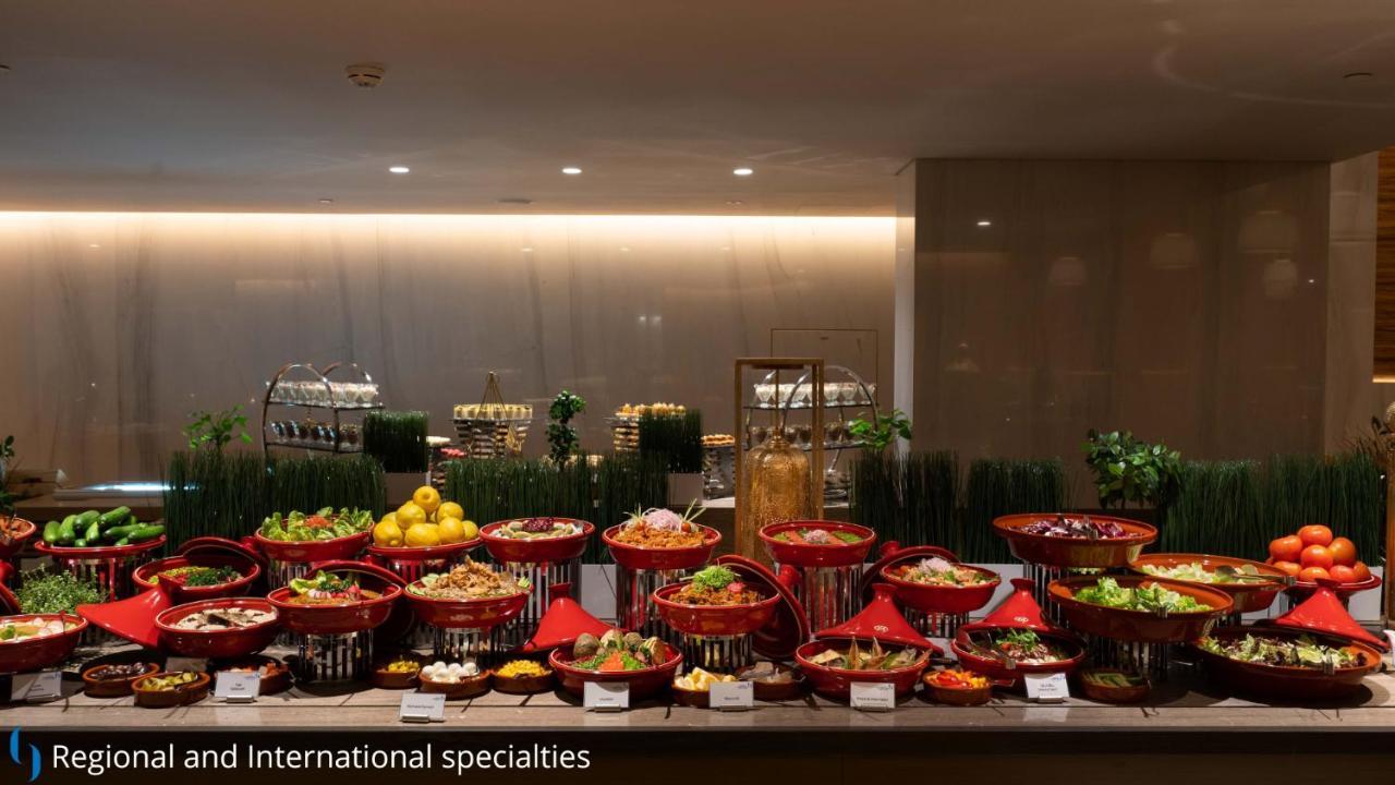 โรงแรมแกรนด์ คอสโมโพลิตัน - ดูไบ ภายนอก รูปภาพ The photo displays a buffet setup featuring a variety of dishes arranged in decorative baskets. There are multiple red baskets filled with a range of colorful dishes, including salads, fruits, and other culinary specialties. The background has a mode